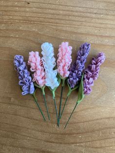 four different colored flowers sitting on top of a wooden table