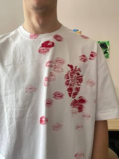 a man wearing a white t - shirt with red lipstick prints on it