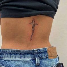 a woman's lower back tattoo with a shark on her left side ribcage