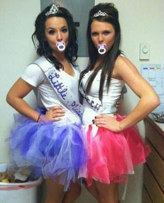 two beautiful women standing next to each other in front of a refrigerator wearing crowns and dresses