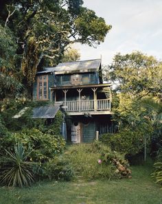 an old house in the middle of some trees and bushes, surrounded by greenery