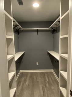 an empty walk in closet with white shelves