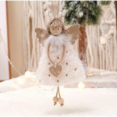 a white angel ornament hanging from a string on top of snow covered ground