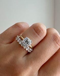 a woman's hand with a diamond ring on top of her finger and two diamonds in the middle