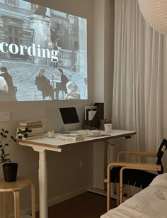 a room with a desk, chair and large screen in it that says recording on the wall