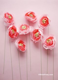 pink paper flowers with gold centers are arranged in a row on a light pink background