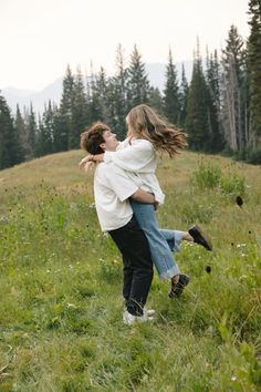 two people are playing in the grass with each other and one person is holding another