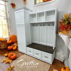 an entryway with white cabinets and pumpkins on the floor