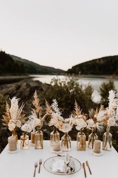 the table is set with flowers, candles and silverware for an outdoor wedding reception