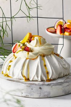 a white cake with fruit on top sitting on a table next to other desserts