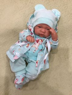 a baby doll that is laying down on the floor wearing a blue outfit and hat