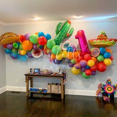 a room filled with balloons and mexican themed decorations on the wall, along with a wooden table