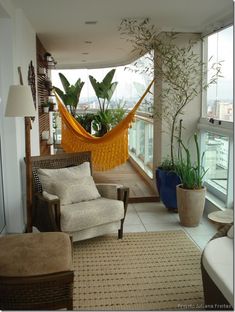 a living room filled with furniture and a hammock hanging from the ceiling next to a window