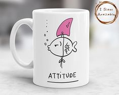 a coffee mug with an image of a fish wearing a pink hat that says attitude