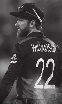 a black and white photo of a man with a beard wearing a baseball uniform holding a bat