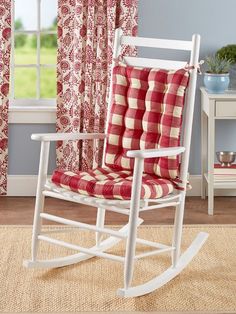 a red and white rocking chair in front of a window