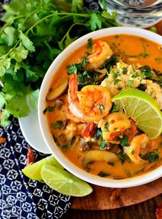 a white bowl filled with shrimp and tortilla soup next to cilantro