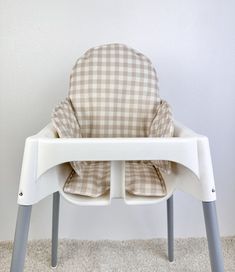 a white and brown checkered highchair with seat cover on it's back