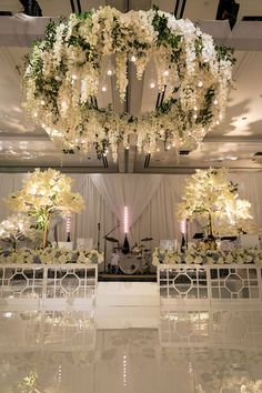 an elegant wedding setup with white flowers and chandelier hanging from the ceiling above