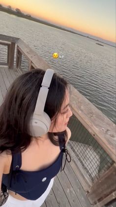 a woman with headphones on looking at the water