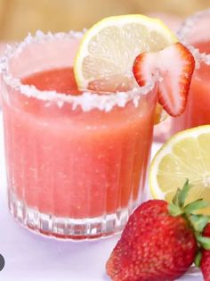 two glasses filled with watermelon and lemonade next to sliced strawberries on a white surface