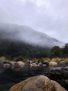 a person swimming in a body of water with mountains in the backgrouds