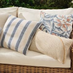 a wicker couch with several pillows on it