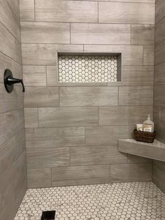 a walk in shower with hexagonal tile on the floor and shelves above it