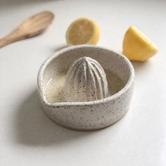 a small bowl with some fruit in it on a table next to lemons and a wooden spoon