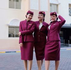 three women in red uniforms standing next to each other on a brick walkway near a building