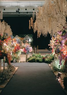 an outdoor wedding ceremony with flowers and chandeliers hanging from the ceiling at night