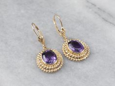 Sophisticated and yet interesting, these earrings feature bright bursts of color from the amethysts and an excellent shine from every facet. The perfect size to transition from day to evening, these lovely earrings are sure to be a favorite of your jewelry wardrobe. Metal: 14K Yellow Gold Gem: 2 Amethyst Gem Measurements: 9.8 x 7.7 mm, Oval Earrings Length: 34 mm Earrings Width: 15 mm Marks: “14K” Stamped on the Findings Purple Oval Fine Jewelry Earrings, Oval Amethyst Earrings With Gemstone Accents, Round Purple Earrings With Gemstone Accents, Purple Gemstone Accented Round Earrings, Purple Gemstone Accent Round Earrings, Purple Round Earrings With Gemstone Accents, Purple Oval Earrings With Gemstone Accents, Purple Faceted Earrings For Anniversary, Jewelry Wardrobe