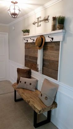 a wooden bench with pillows and hats on top of it next to a white wall