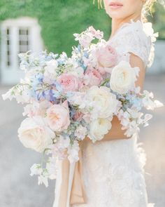 a woman holding a bouquet of flowers in her hands and looking at the camera while wearing a wedding dress