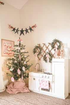 a small christmas tree sitting in the corner of a room next to a stove top oven