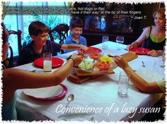 three children sitting at a table with plates of food and drinks in front of them