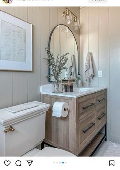 a white toilet sitting next to a wooden vanity in a bathroom under a large mirror