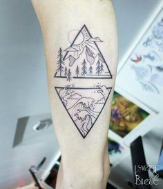 a person with a tattoo on their leg that has mountains and trees in the background