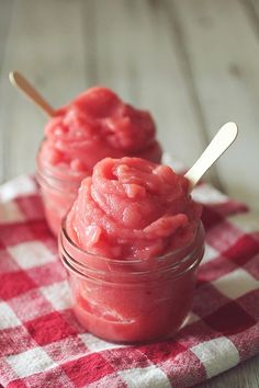 two small jars filled with food on top of a checkered table cloth