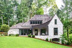 a large white brick house in the middle of a lush green yard with lots of trees