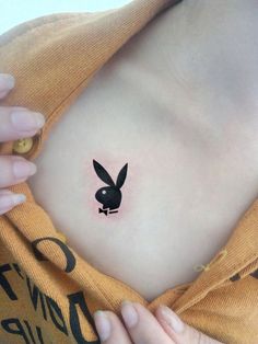 a woman's stomach with a small black bunny tattoo on it