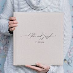 a woman holding up a book with writing on it