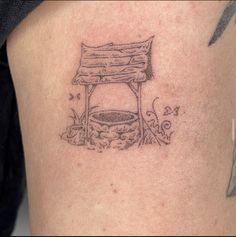 a tattoo on the back of a woman's thigh with a bench and flowers