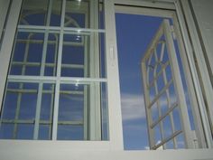 an open window with the sky reflected in it