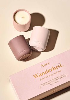 two candles sitting on top of a pink box next to a white container with the word, aery wanderlust