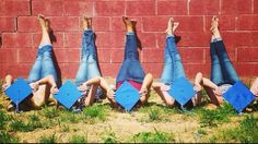 four people laying on their back in front of a brick wall with graduation caps and diplomas