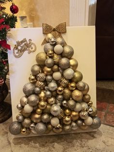 a christmas tree made out of ornaments on top of a white card with a gold bow