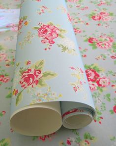 a roll of wrapping paper on top of a floral tablecloth with pink and green flowers