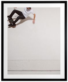 a man riding a skateboard up the side of a wall in front of a white wall