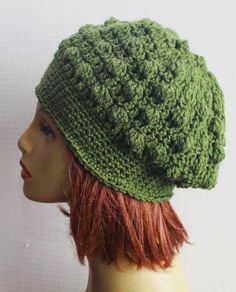 a green crocheted hat on top of a mannequin's head